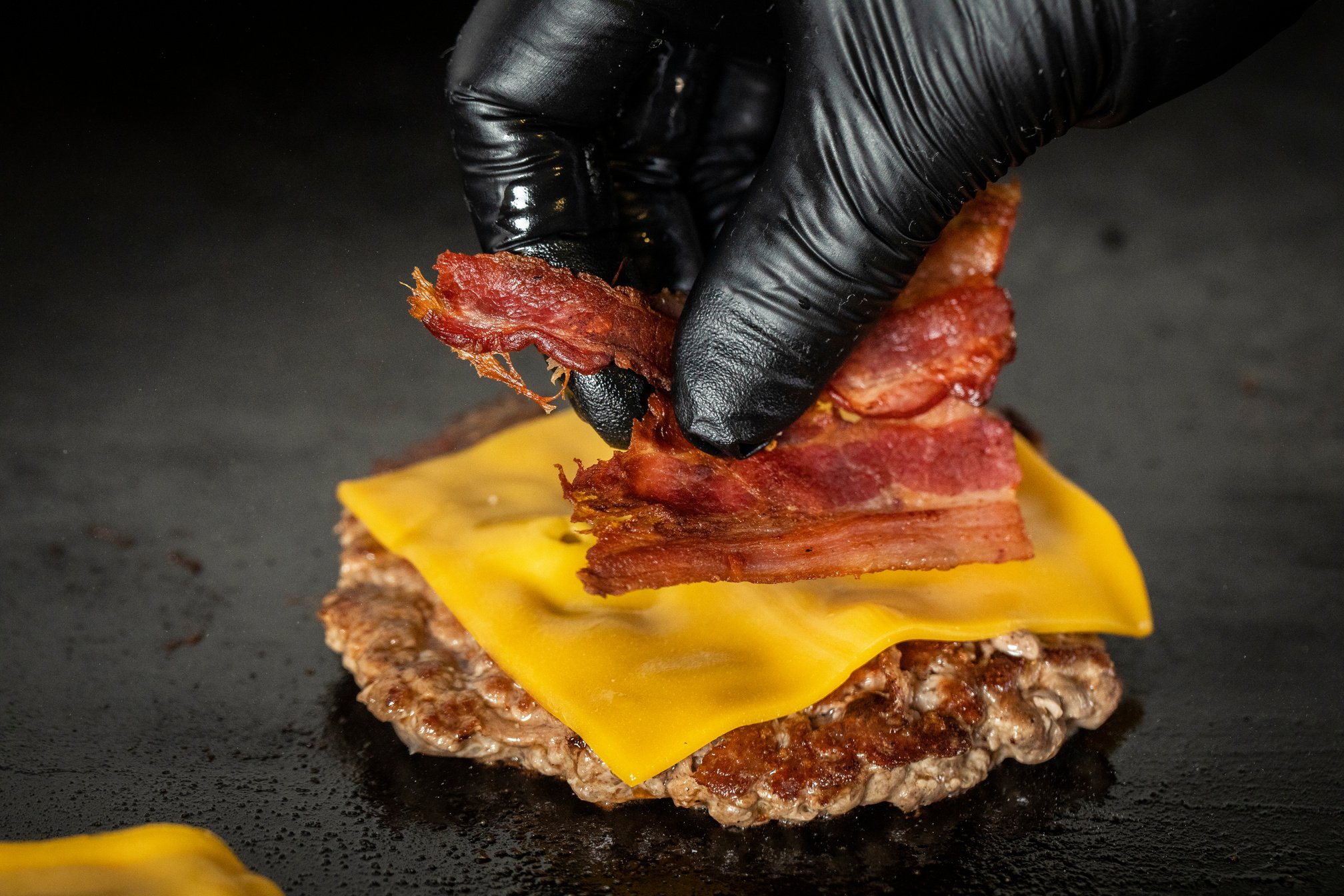 chef with glove putting bacon